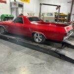 a red car on a wheel alignment machine in a garage