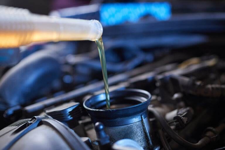 a person pouring oil into a vehicle