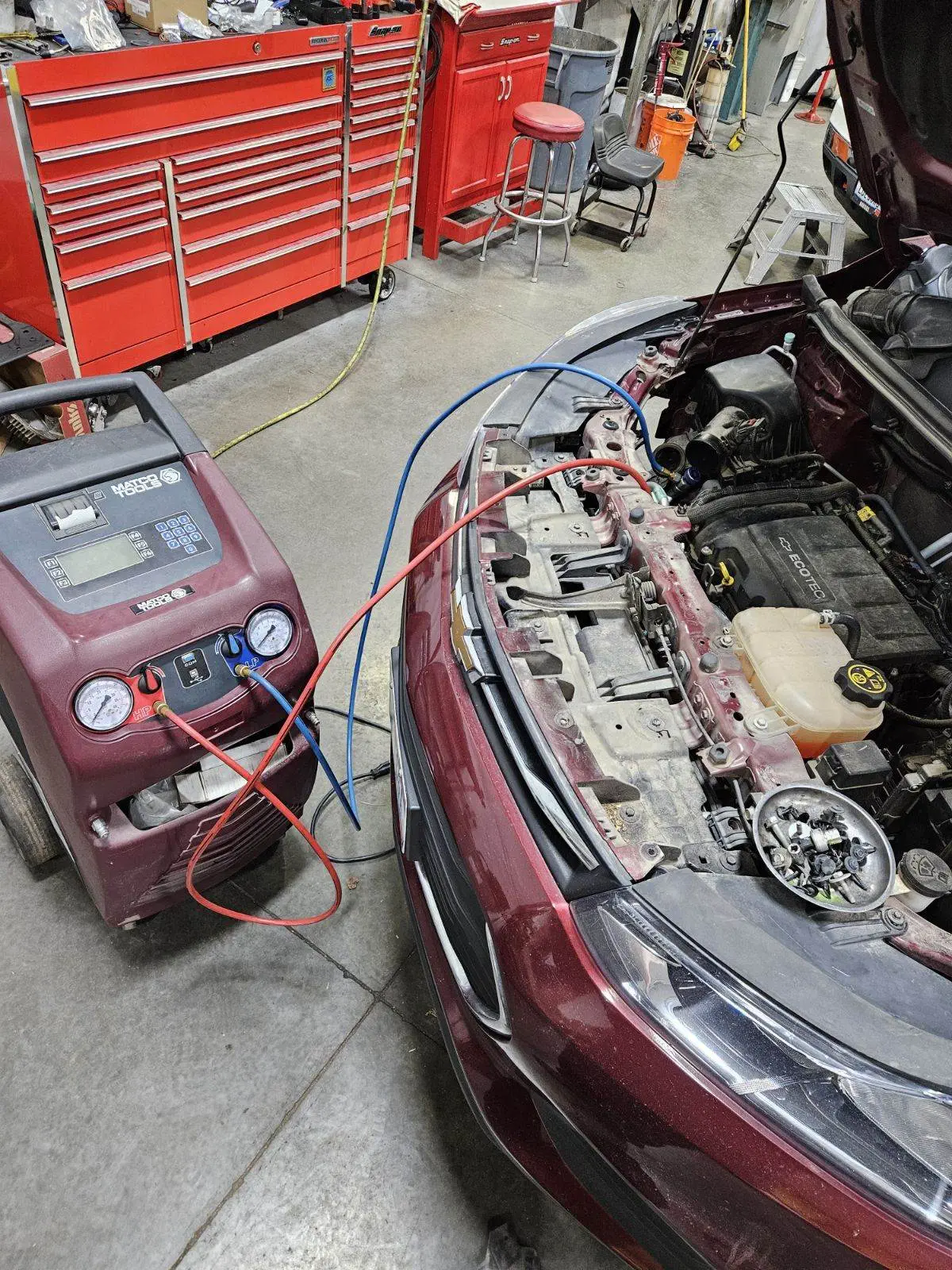 a car with the hood open and a machine in the background