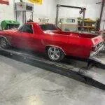 a red car on a wheel alignment machine in a garage