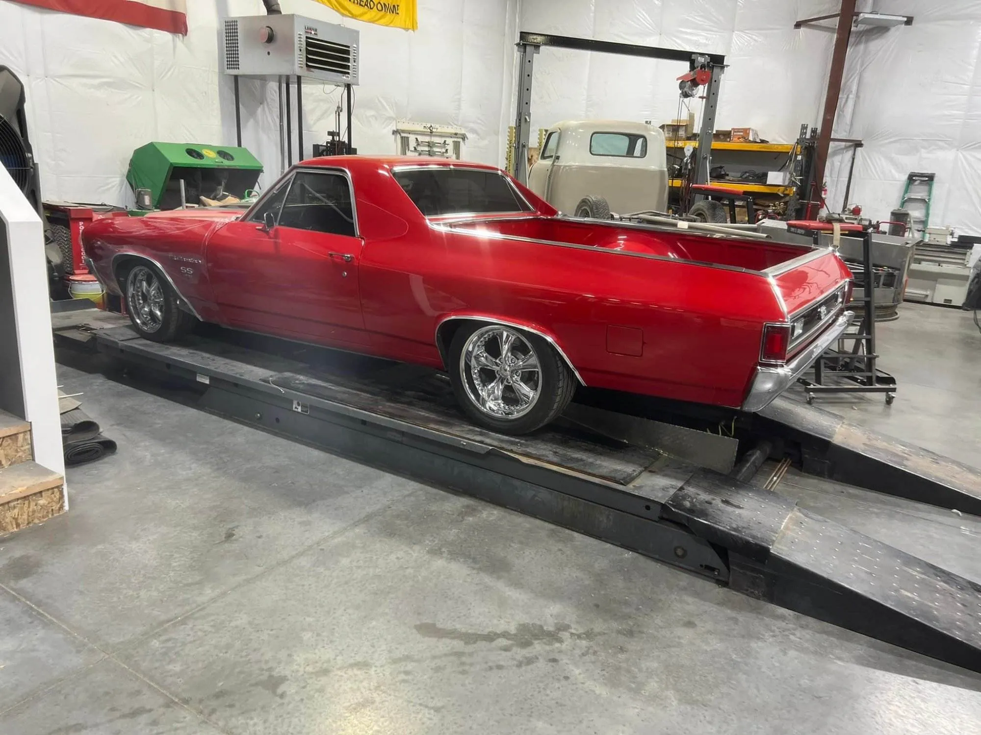 a red car on a wheel alignment machine in a garage